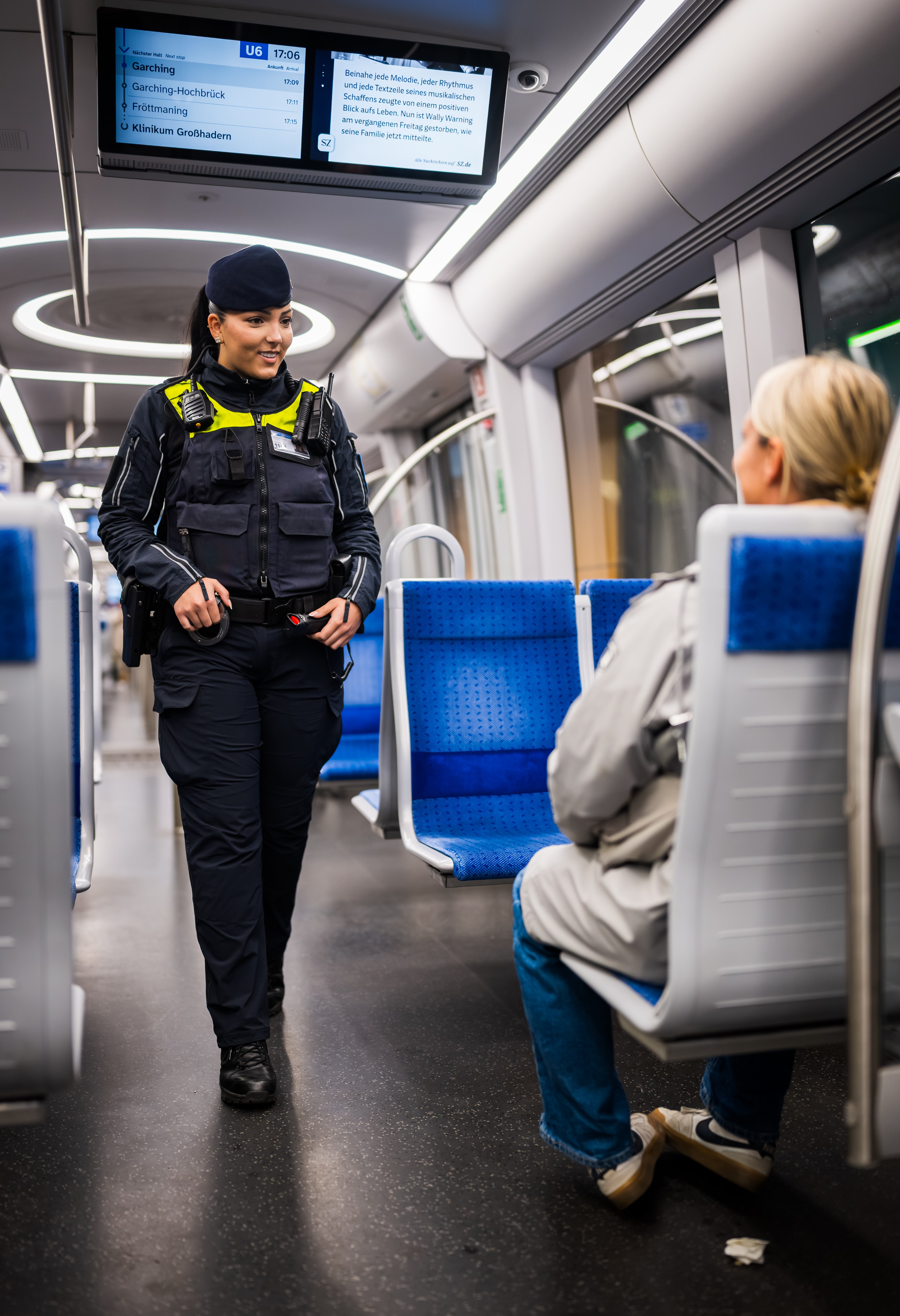A Münchner U-Bahnwache guard speaking to a passenger on a train.