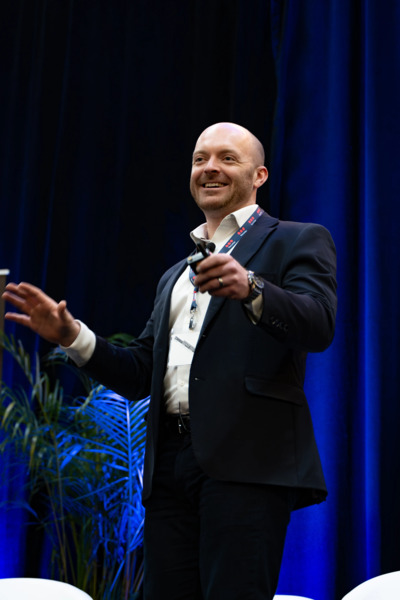 Man in a suit presenting on stage.